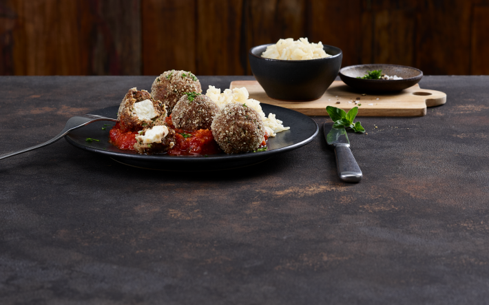 Hackbällchen auf einem Teller mit Feta und Tomatensauce