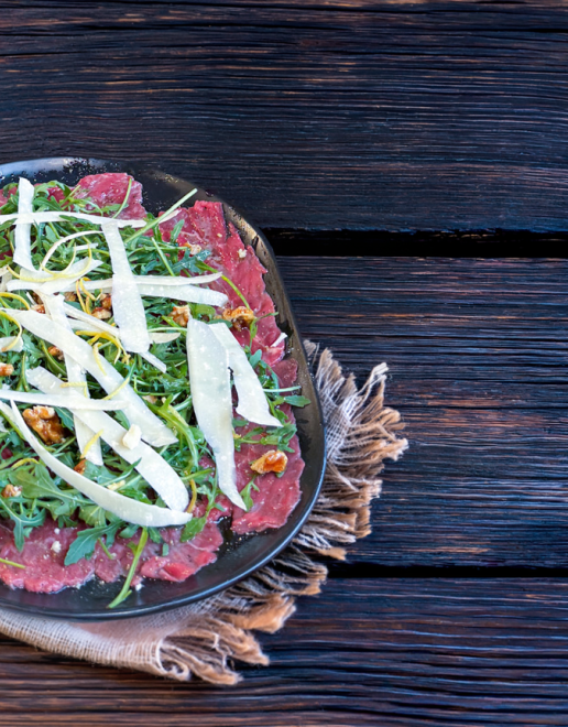 Carpaccio vom Schweizer Rind mit karamellisierten Baumnüssen, Parmesansplitter, Zitronenzesten und Rucola